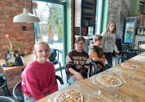 uczniowie przy przygotowanych przez siebie pizzach zanim zostały upieczone