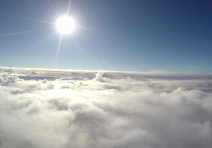 Zdjęcie wykonane znad warstwy chmur, w kadrze jasno świecące słońce.