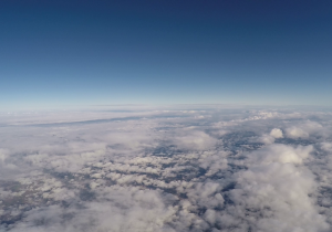 Zdjęcie pokazujące górne warstwy atmosfery. Poniżej warstwa chmur przypominająca watę, niebo ma intensywny niebieski kolor.